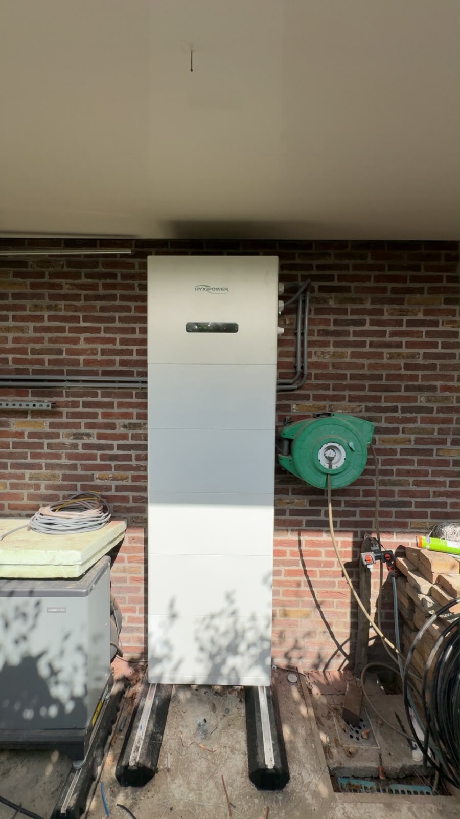 HyxiPower thuisbatterij tegen bakstenen buitenmuur